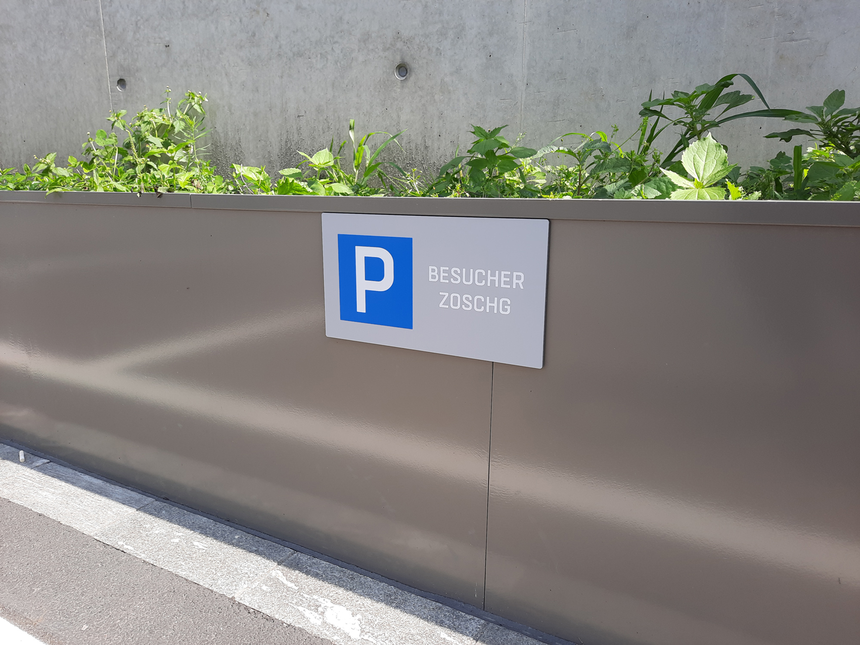 Parkplatzschild auf Blumenbeet geklebt
